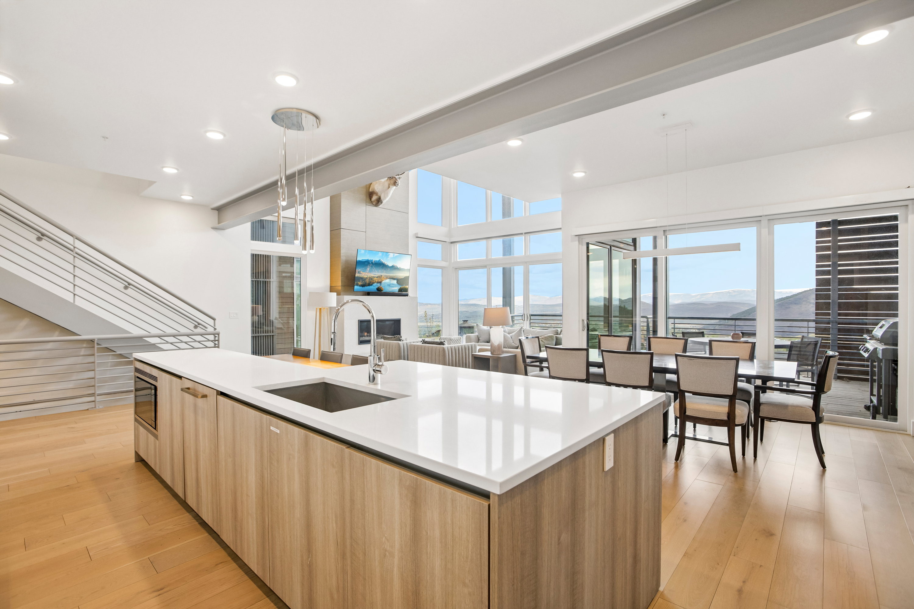 Contemporary kitchen island featuring light wood-finish cabinetry, a white countertop, and an undermount sink with a gooseneck faucet