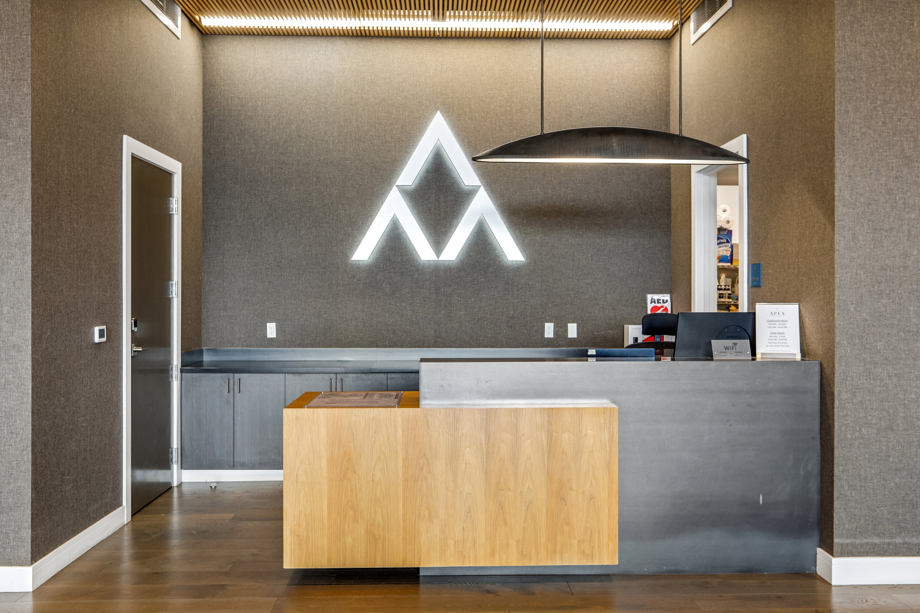 Modern reception area featuring a distinctive illuminated logo, wood-finish flooring, and a sleek, multi-tone reception desk