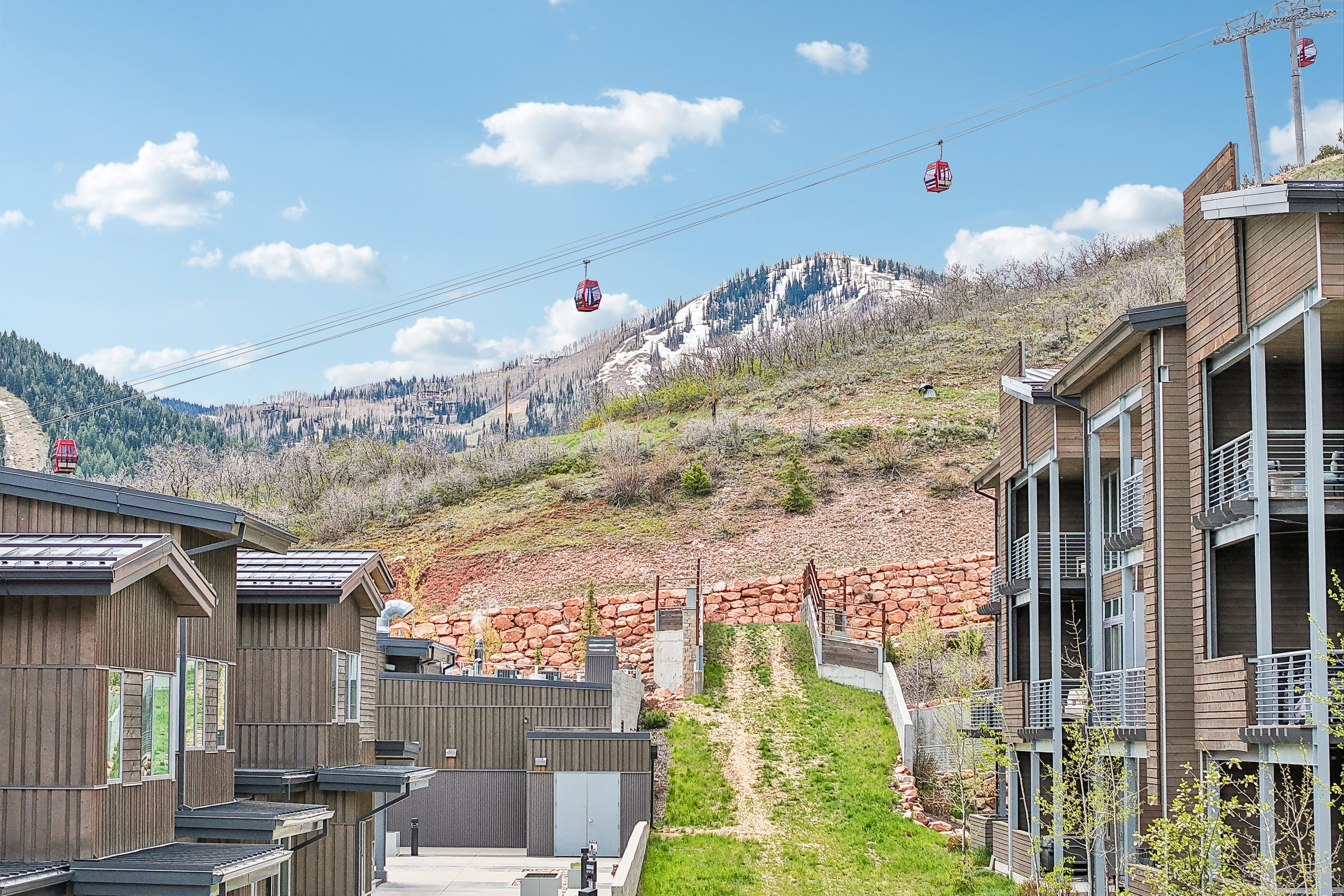Modern mountain residences with wood-finish siding and multiple balconies, set against a backdrop of a mountainous landscape