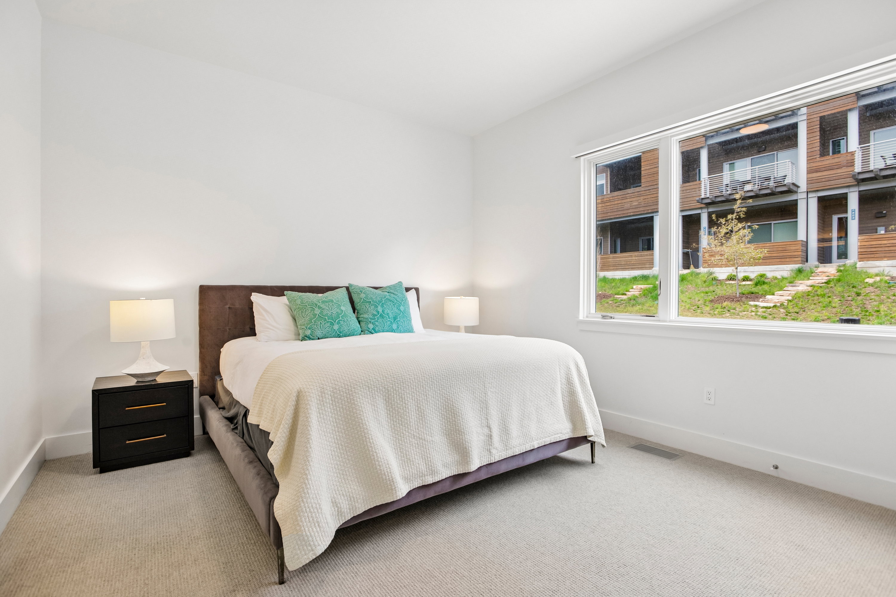 Bright bedroom featuring a large window, plush carpet flooring, white walls, and white trim