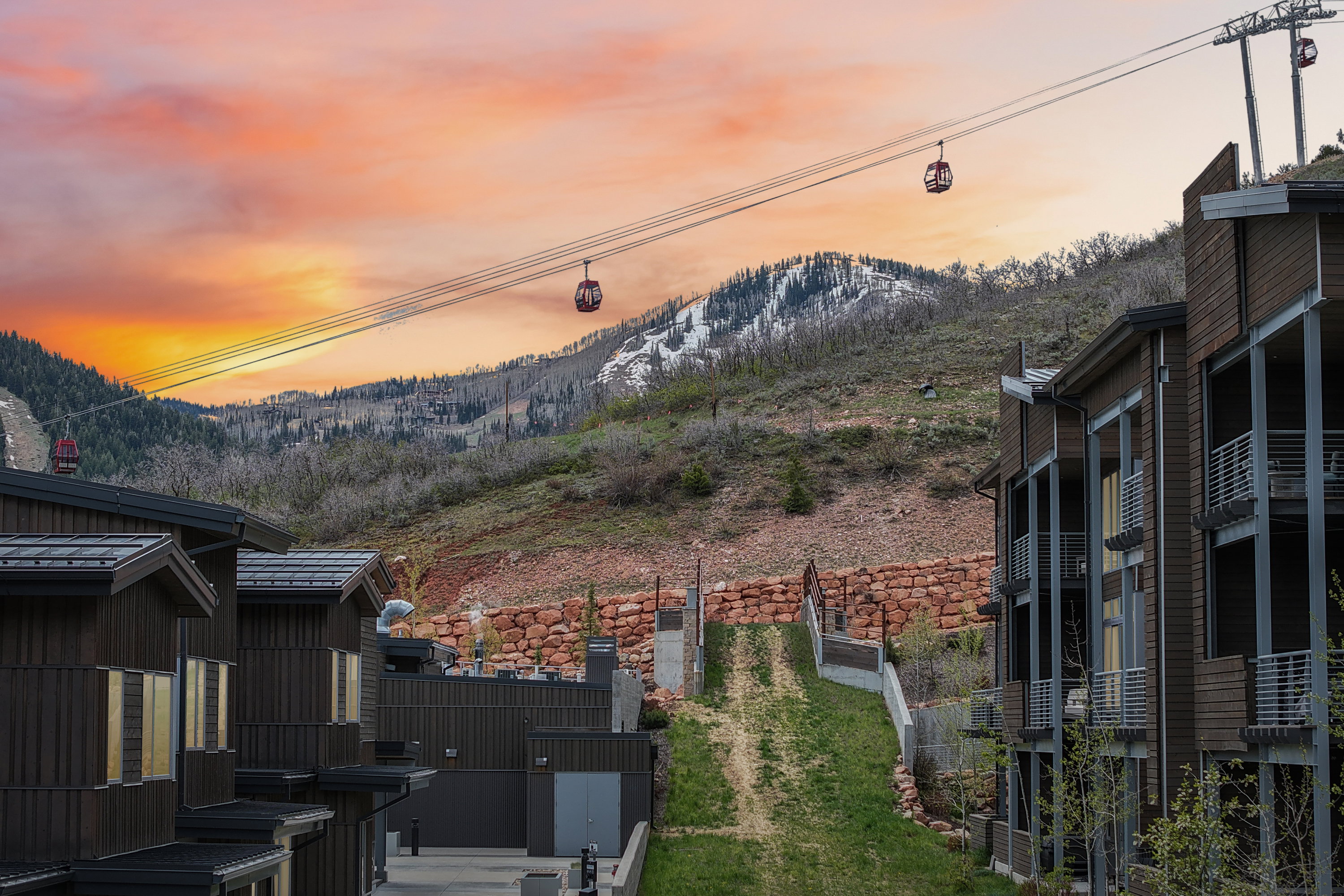 Mountain landscape with gondola system, featuring multi-level buildings with dark siding and balconies