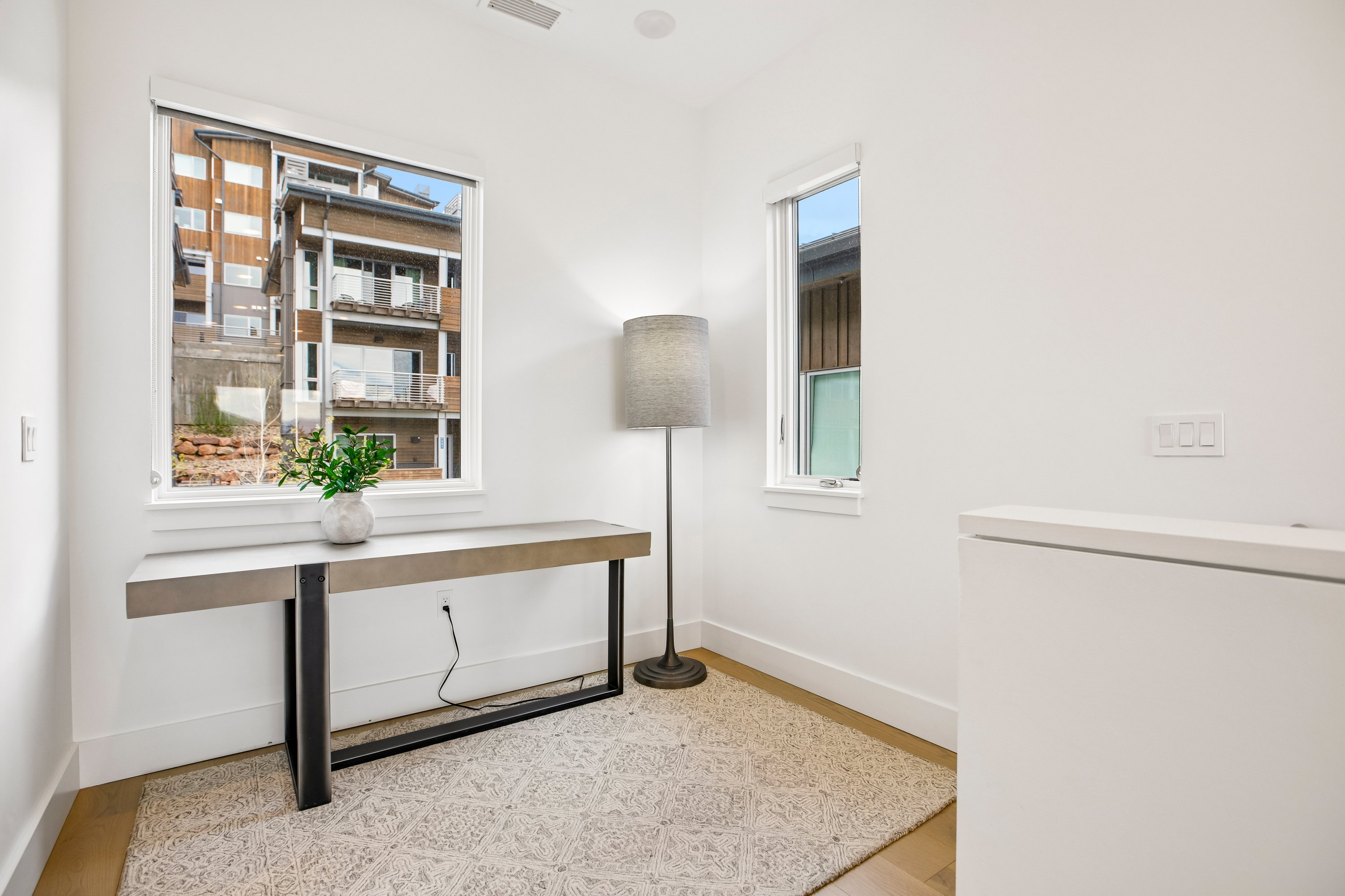 Recessed lighting illuminates this bright space featuring two windows, light wood-finish flooring, and crisp white walls
