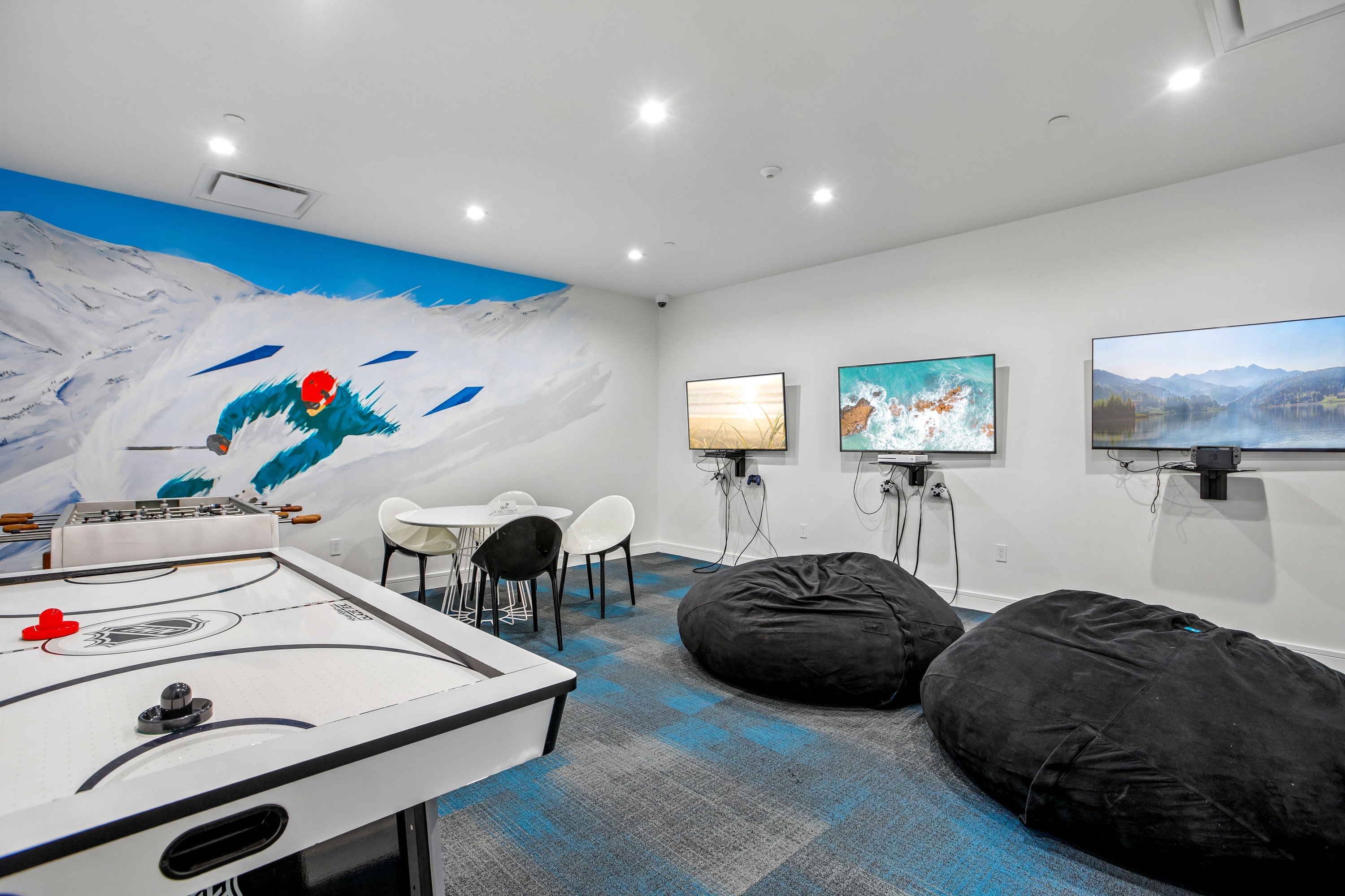 Recreational room featuring a vibrant mural, air hockey table, and foosball table