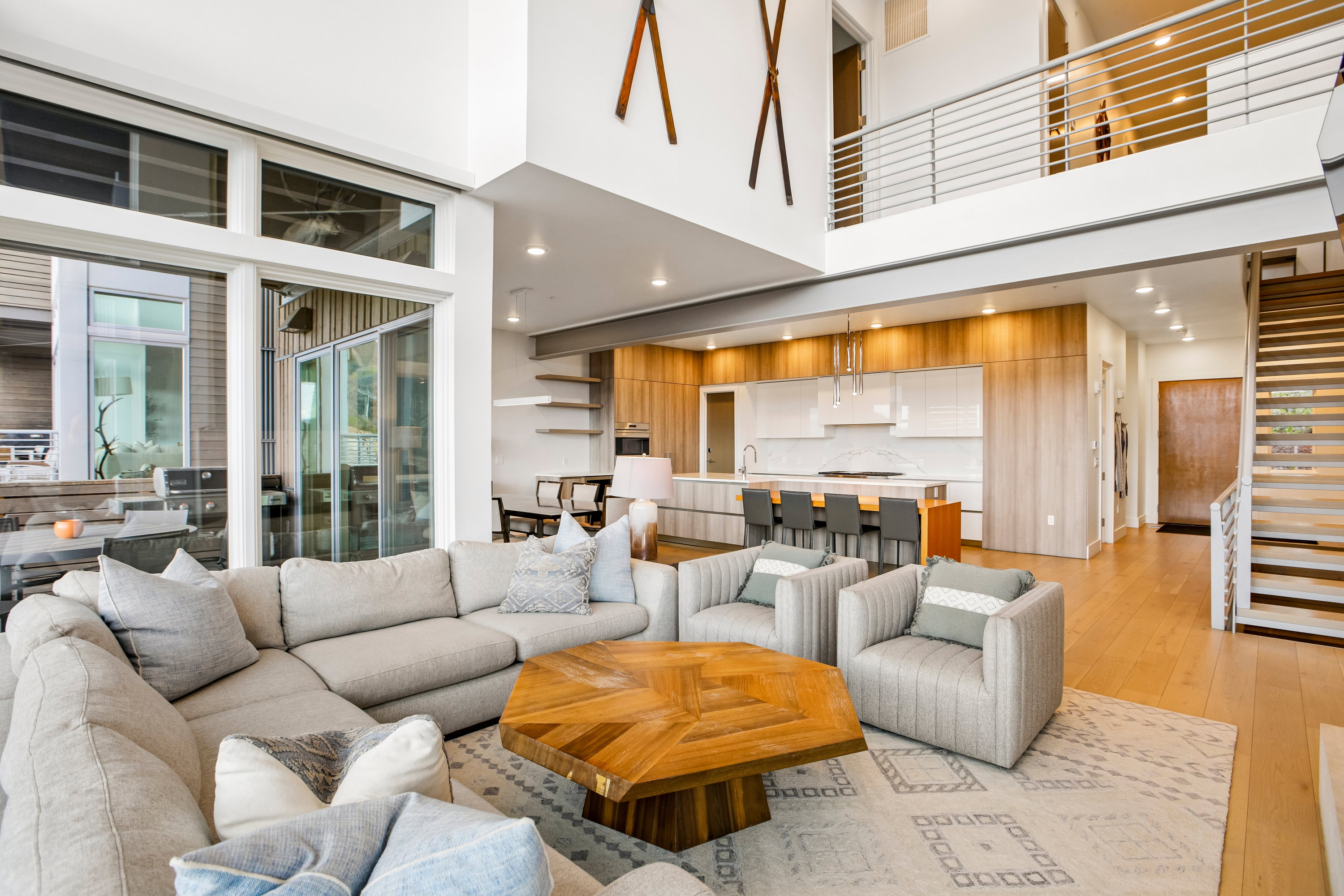 Spacious open-concept living area featuring high ceilings, wood-finish flooring, and large sliding glass doors