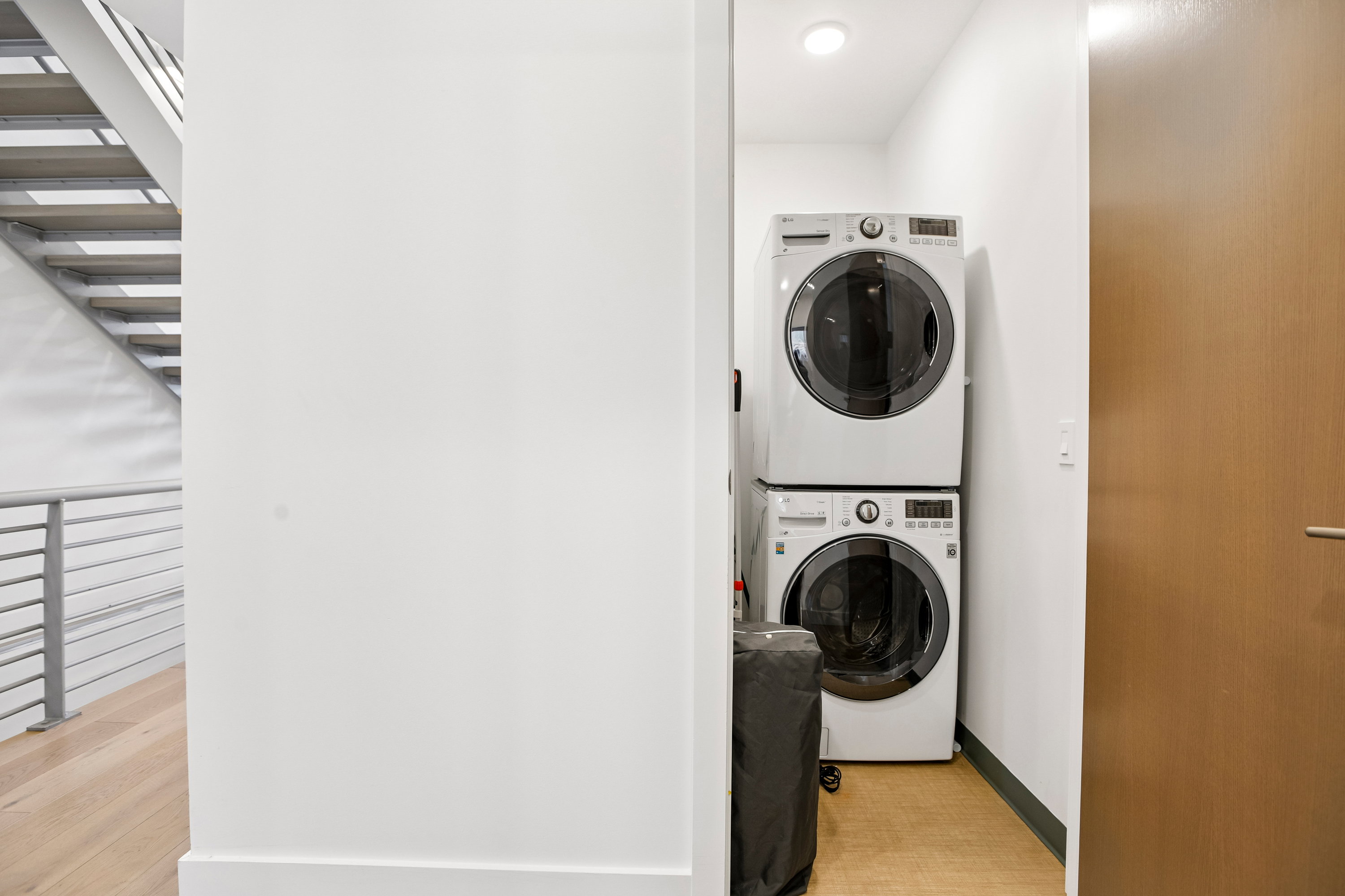 Dedicated laundry nook featuring stacked white front-load washer and dryer units
