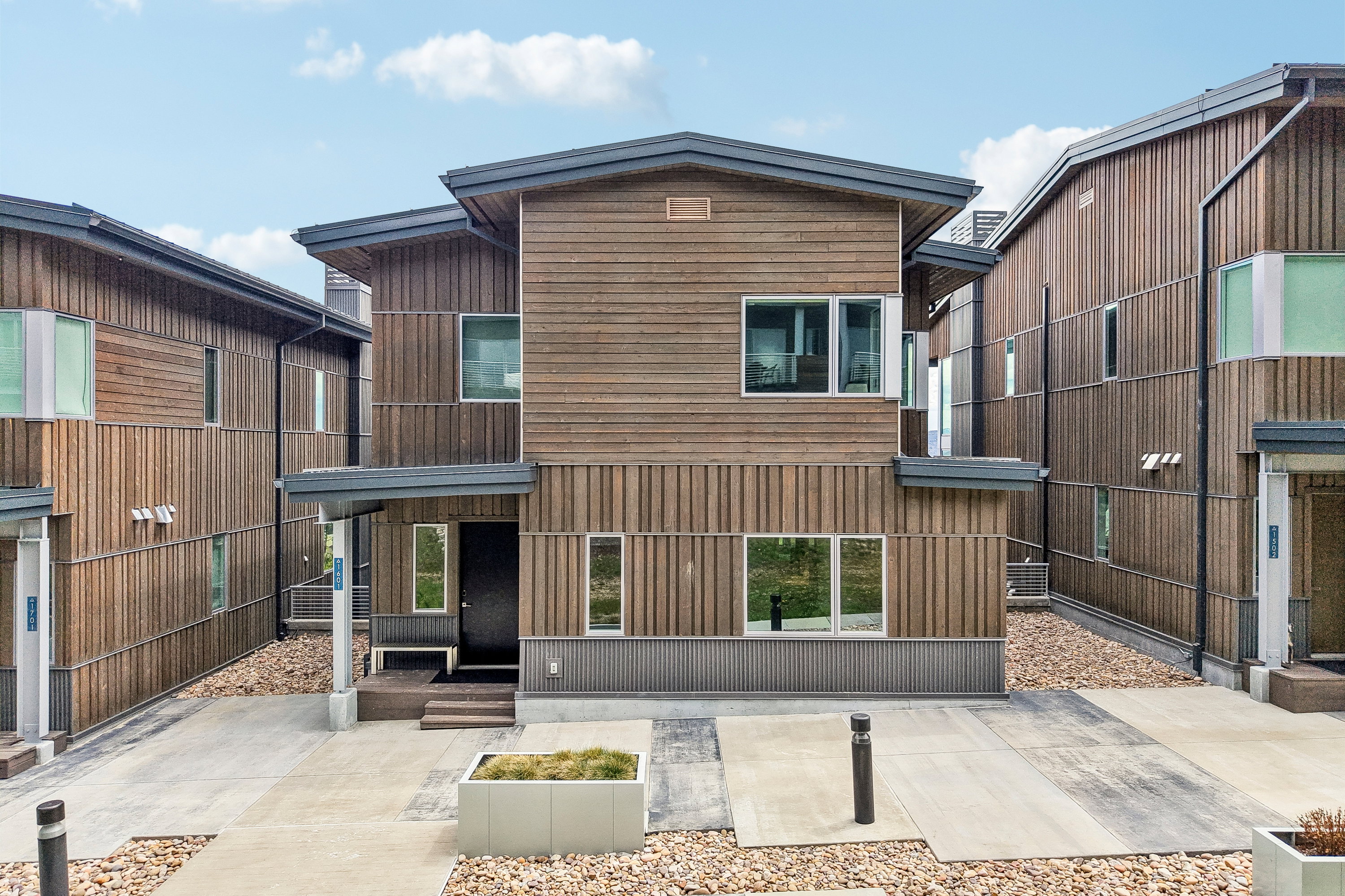 Contemporary facade featuring horizontal and vertical wood siding, a flat roofline, and multiple windows