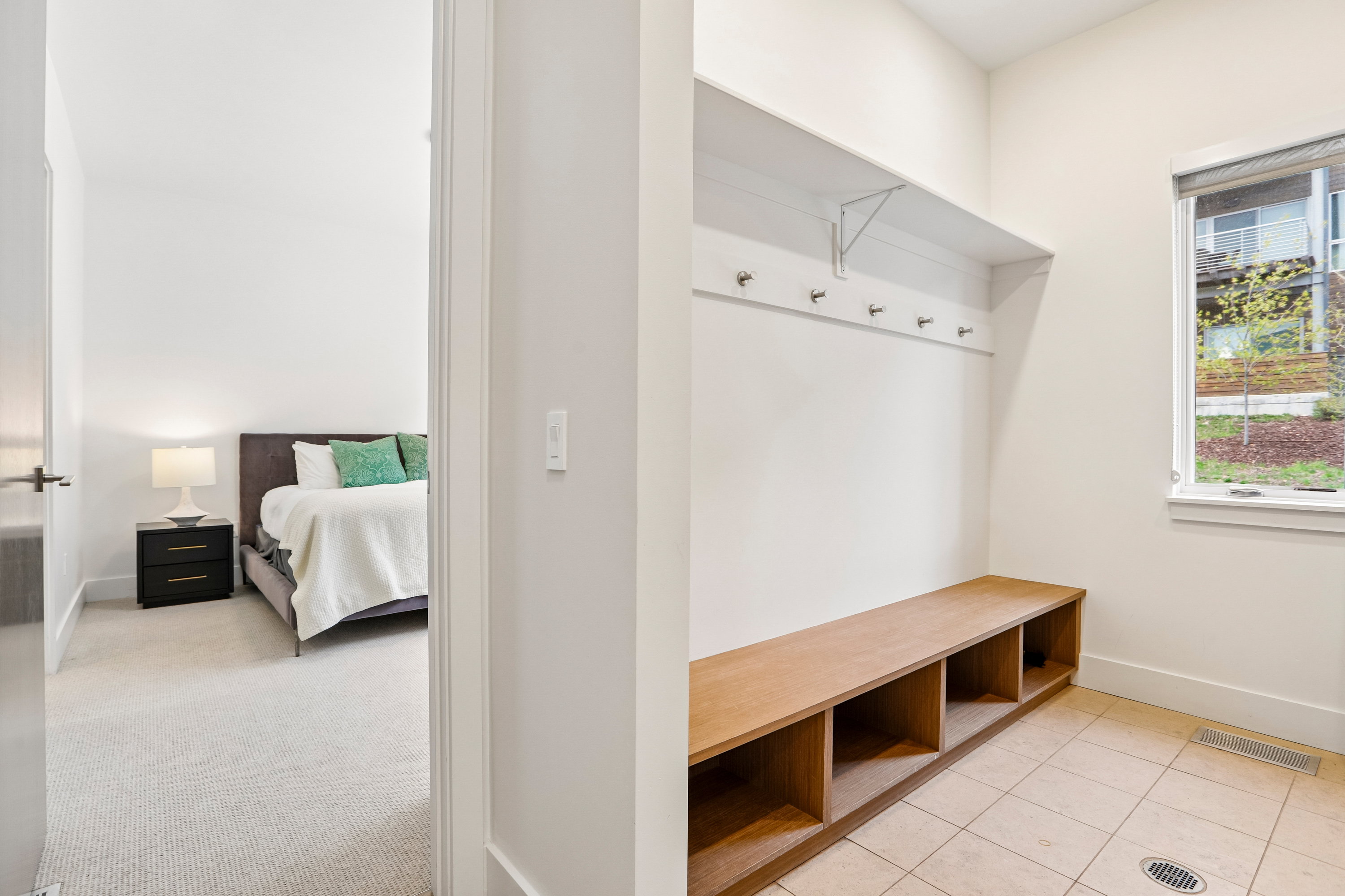 Mudroom featuring a built-in wood-finish bench with cubby storage, a wall-mounted coat rack, and ceramic tile flooring