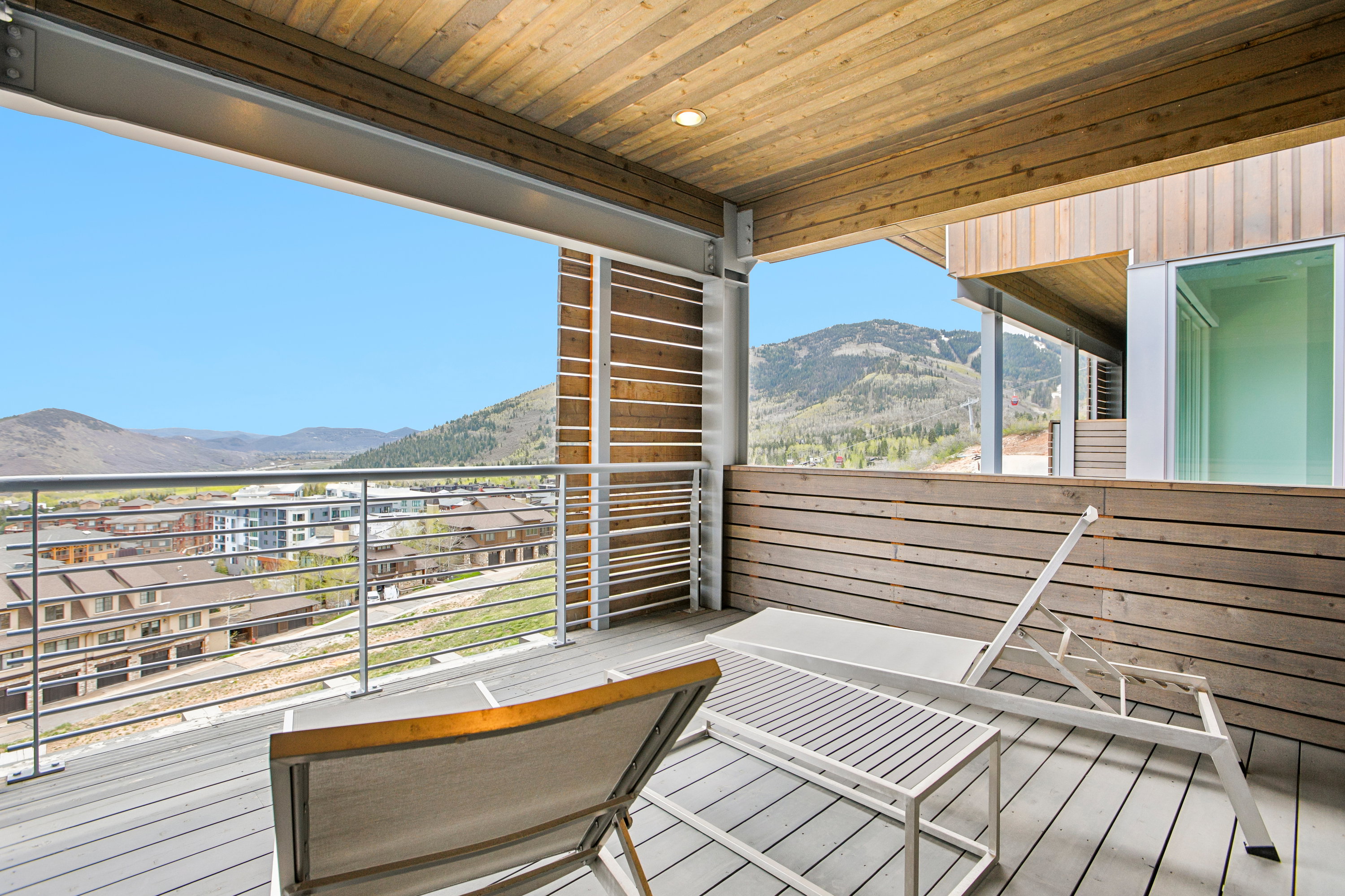 Expansive balcony featuring a composite deck, wood paneling, wood-finish ceiling, and metal railing