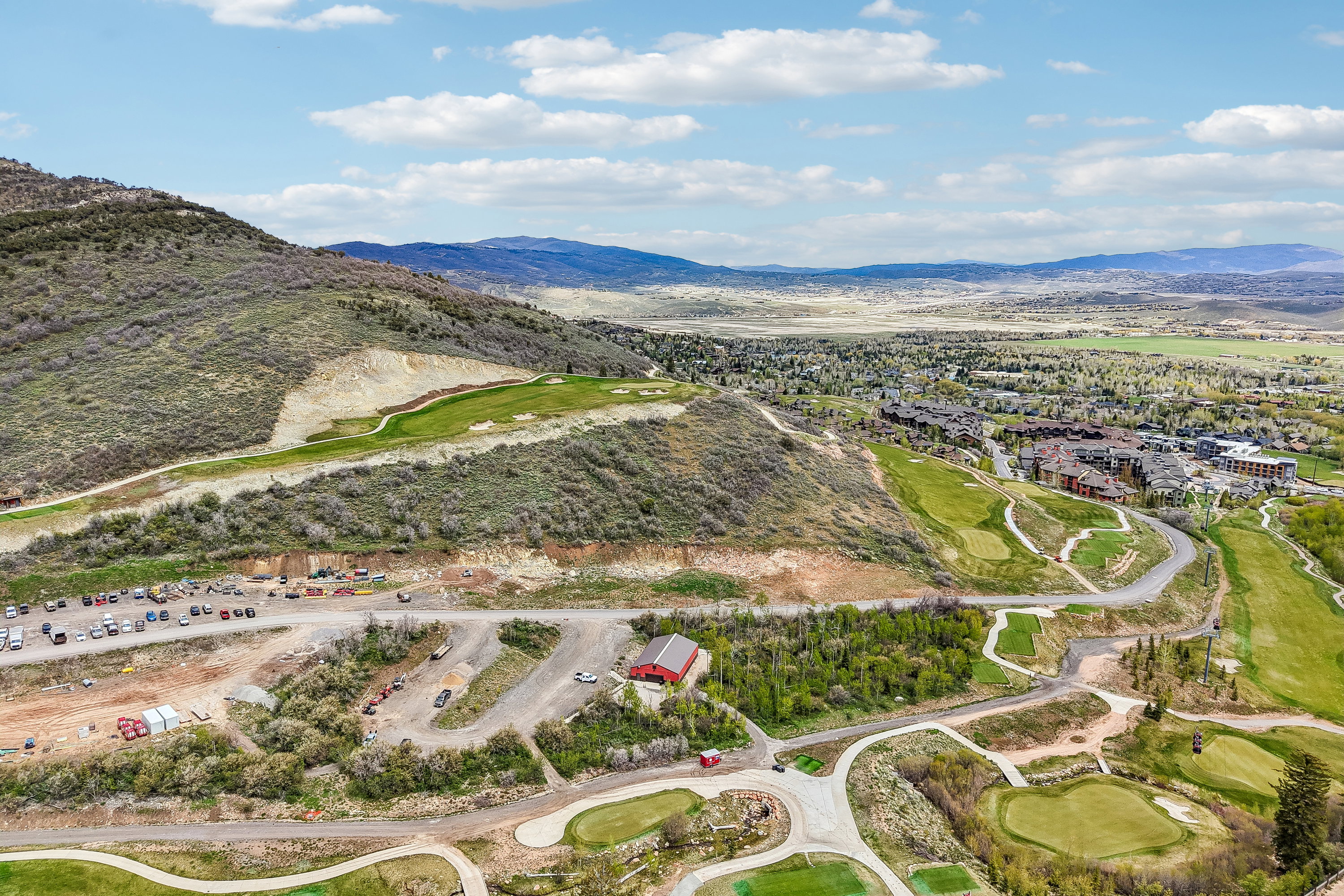 Expansive aerial perspective showcasing a mountainous landscape with a prominent golf course