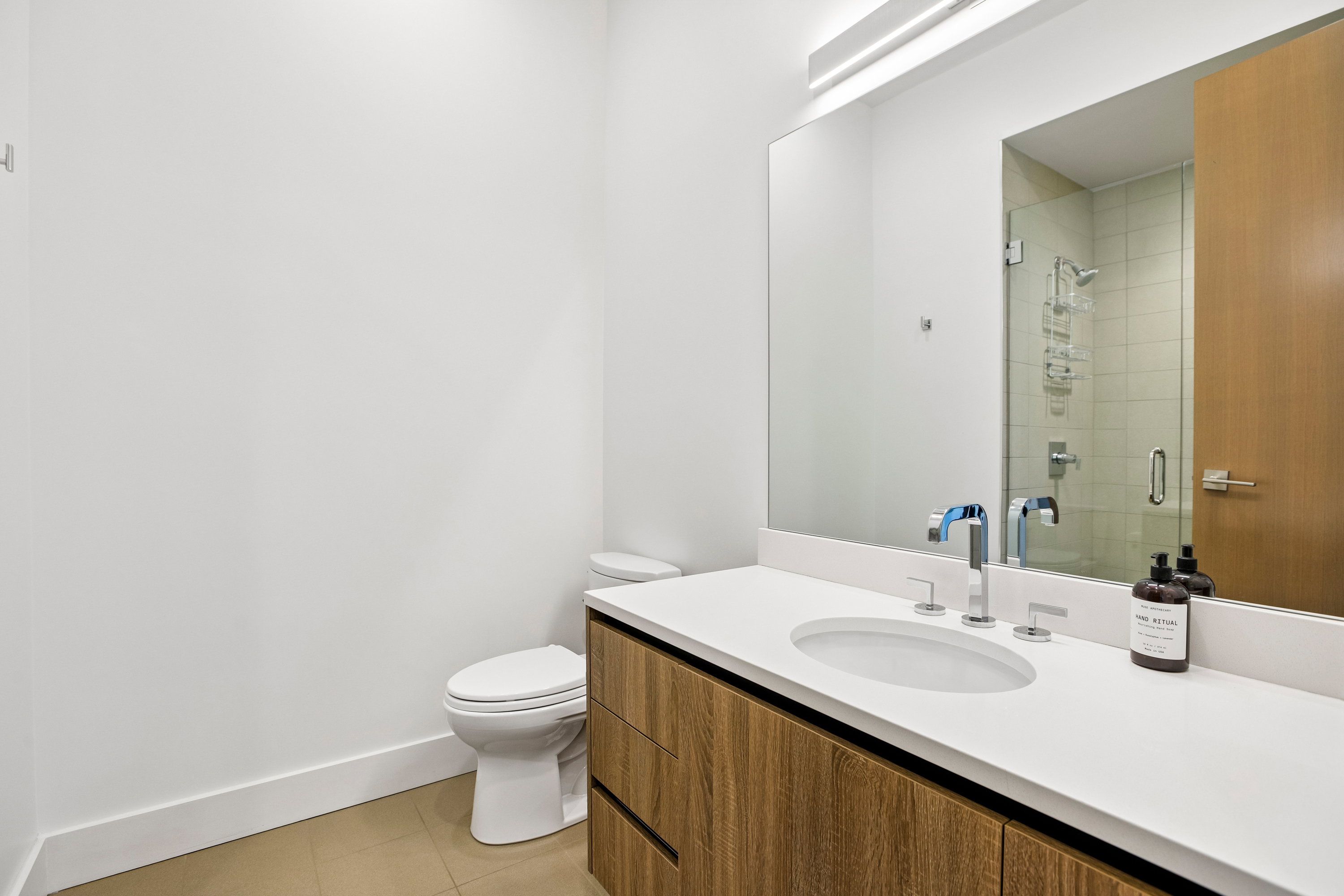 Bathroom featuring a contemporary floating vanity with wood-finish cabinetry, a white countertop, and an undermount sink