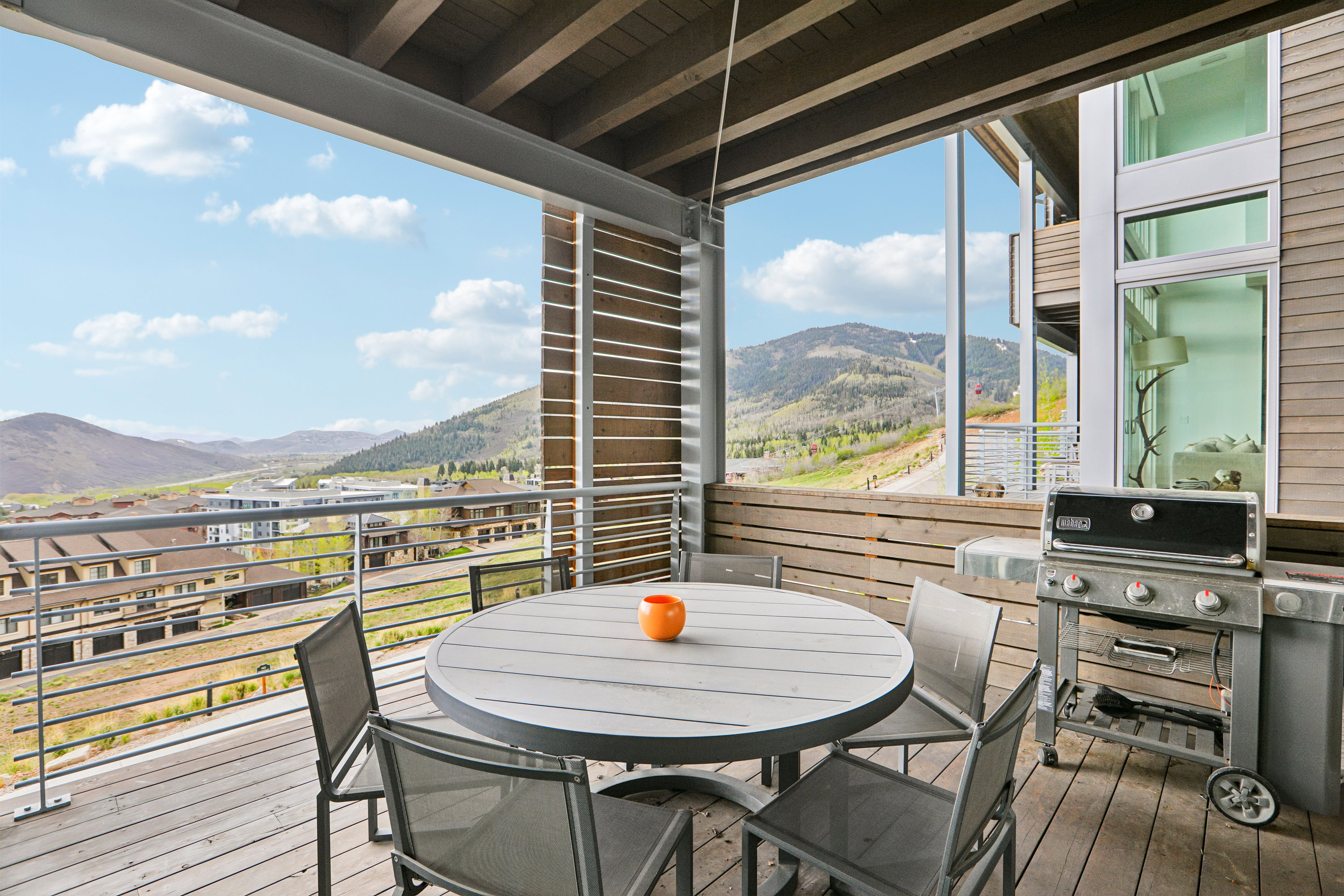 Spacious outdoor deck featuring wood-finish flooring, a wood-slat privacy wall, and metal railing