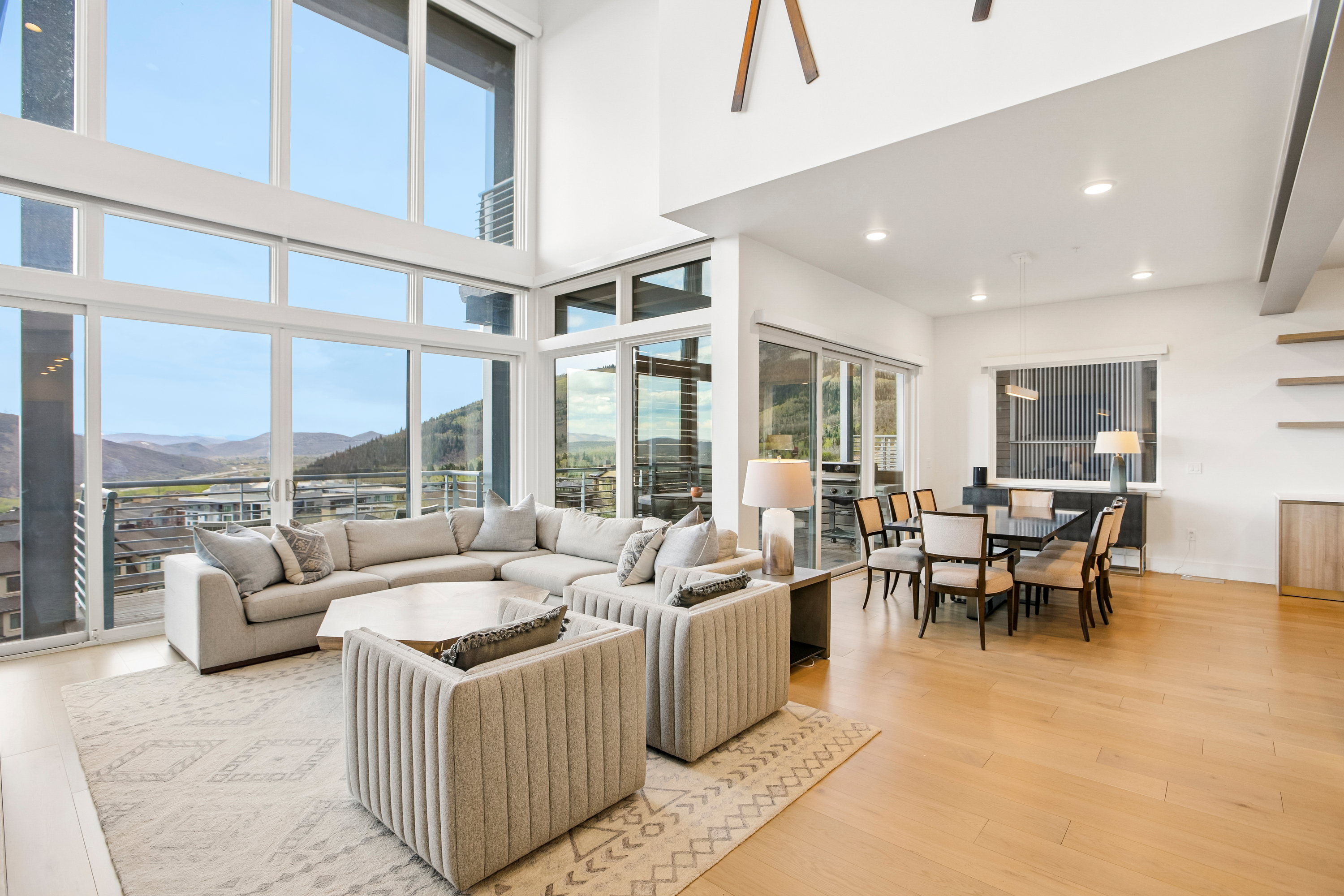Expansive living space featuring floor-to-ceiling windows, wood-finish flooring, and a dining area with recessed lighting