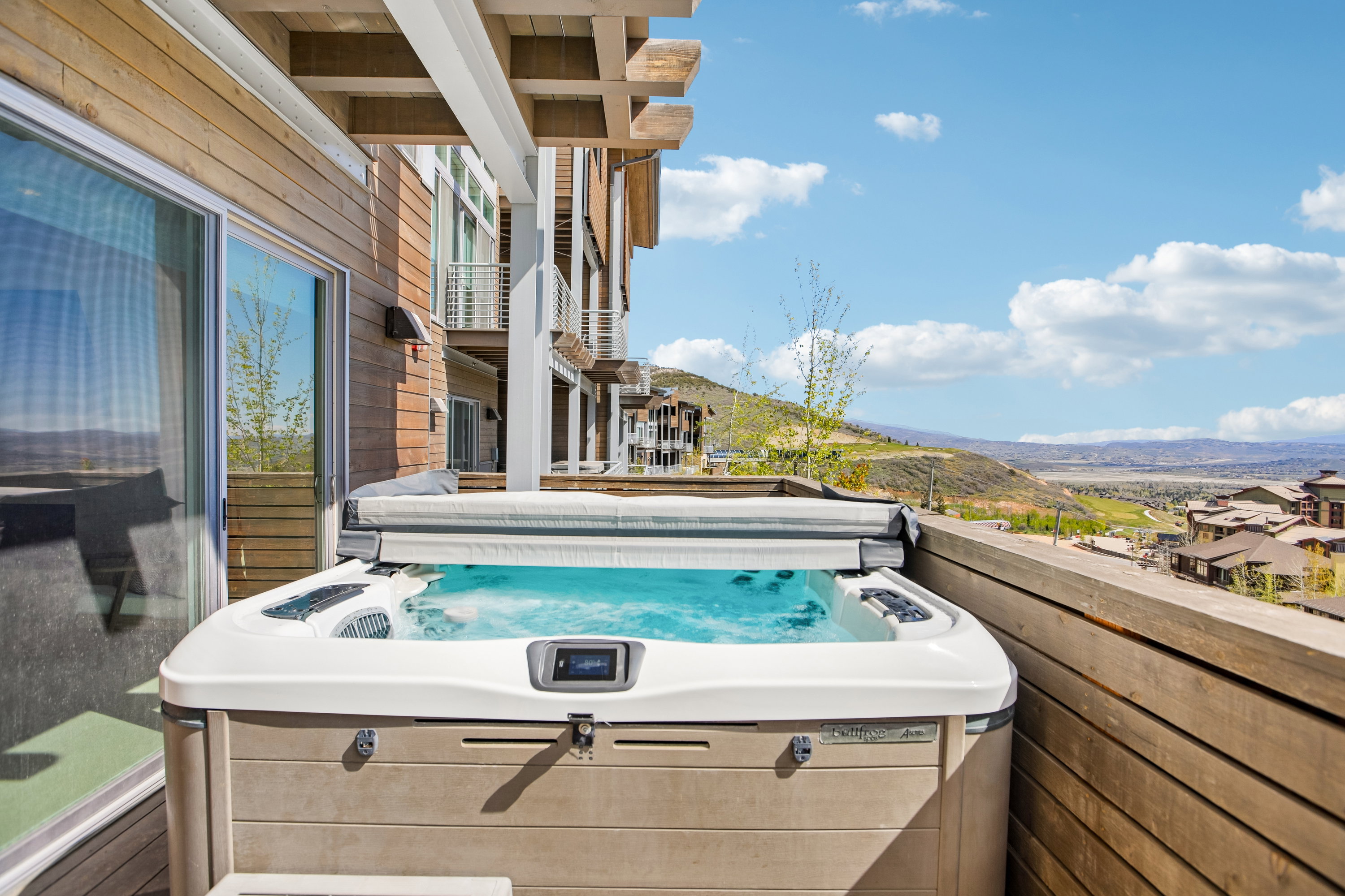 Outdoor spa on a wood-decked patio with a wood-slat privacy wall