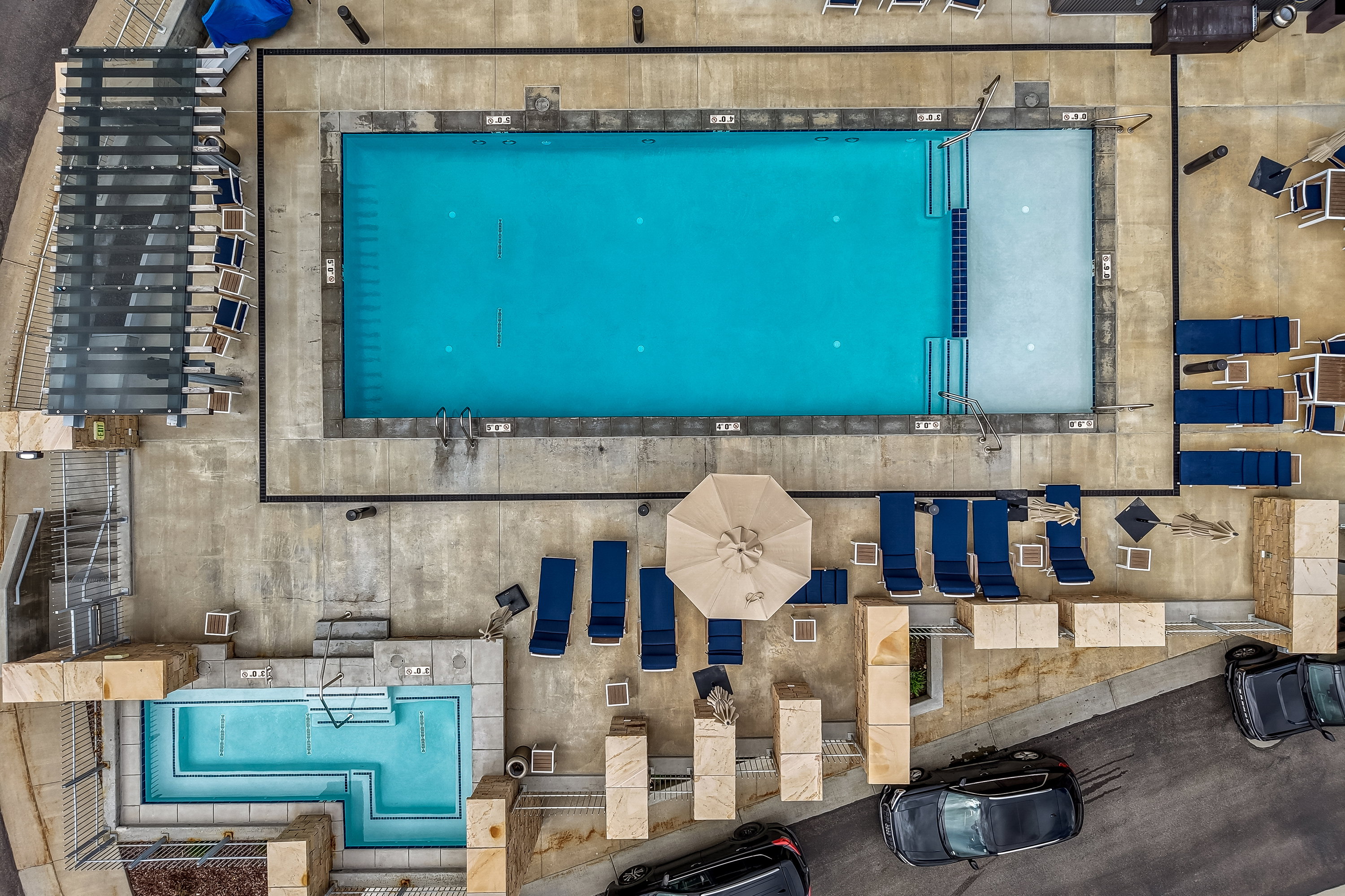 Resort-style pool area featuring a rectangular swimming pool, an adjacent spa, and extensive concrete decking