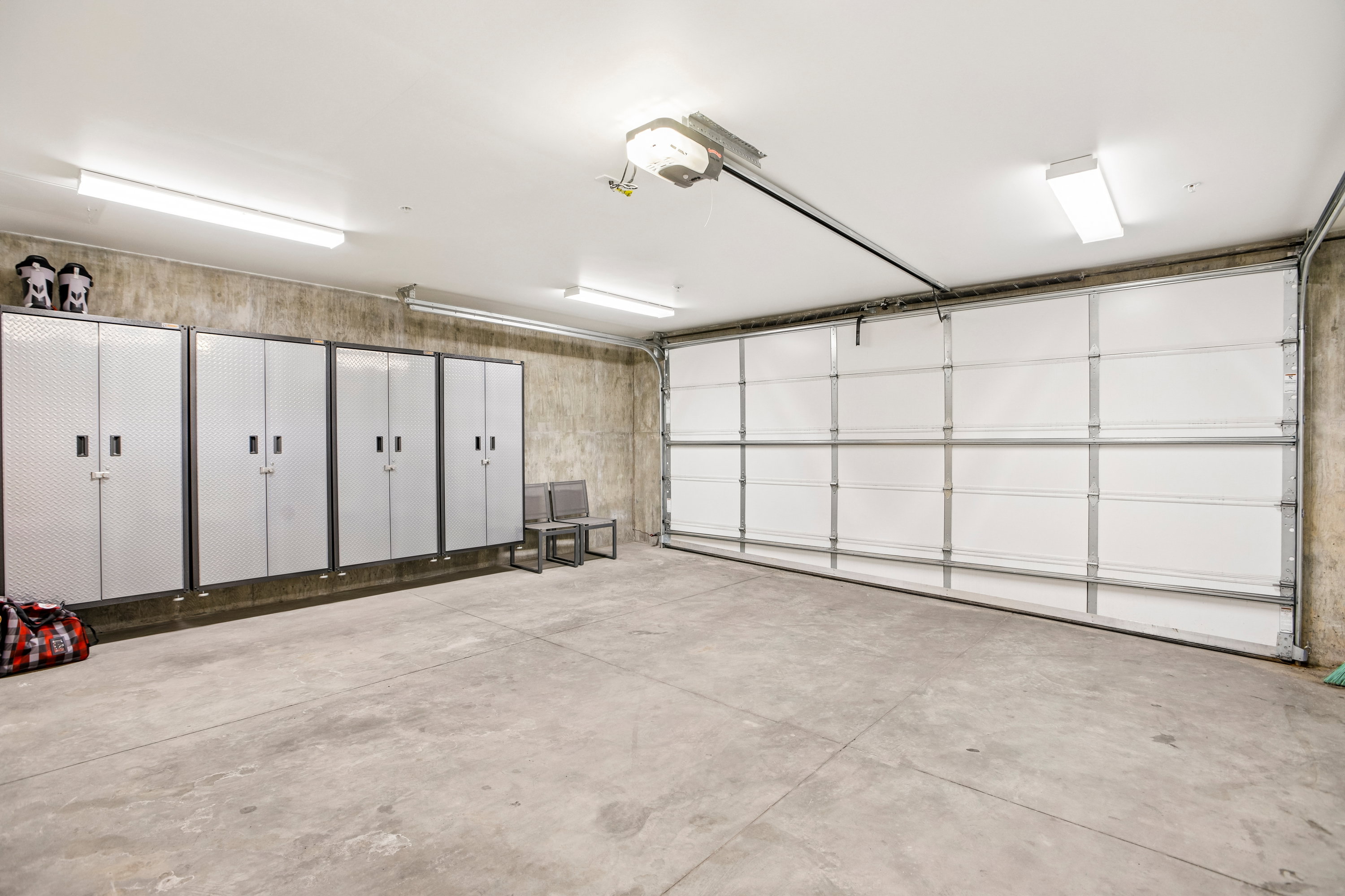 Spacious garage featuring a concrete floor, overhead lighting, an automatic garage door, and built-in storage cabinets