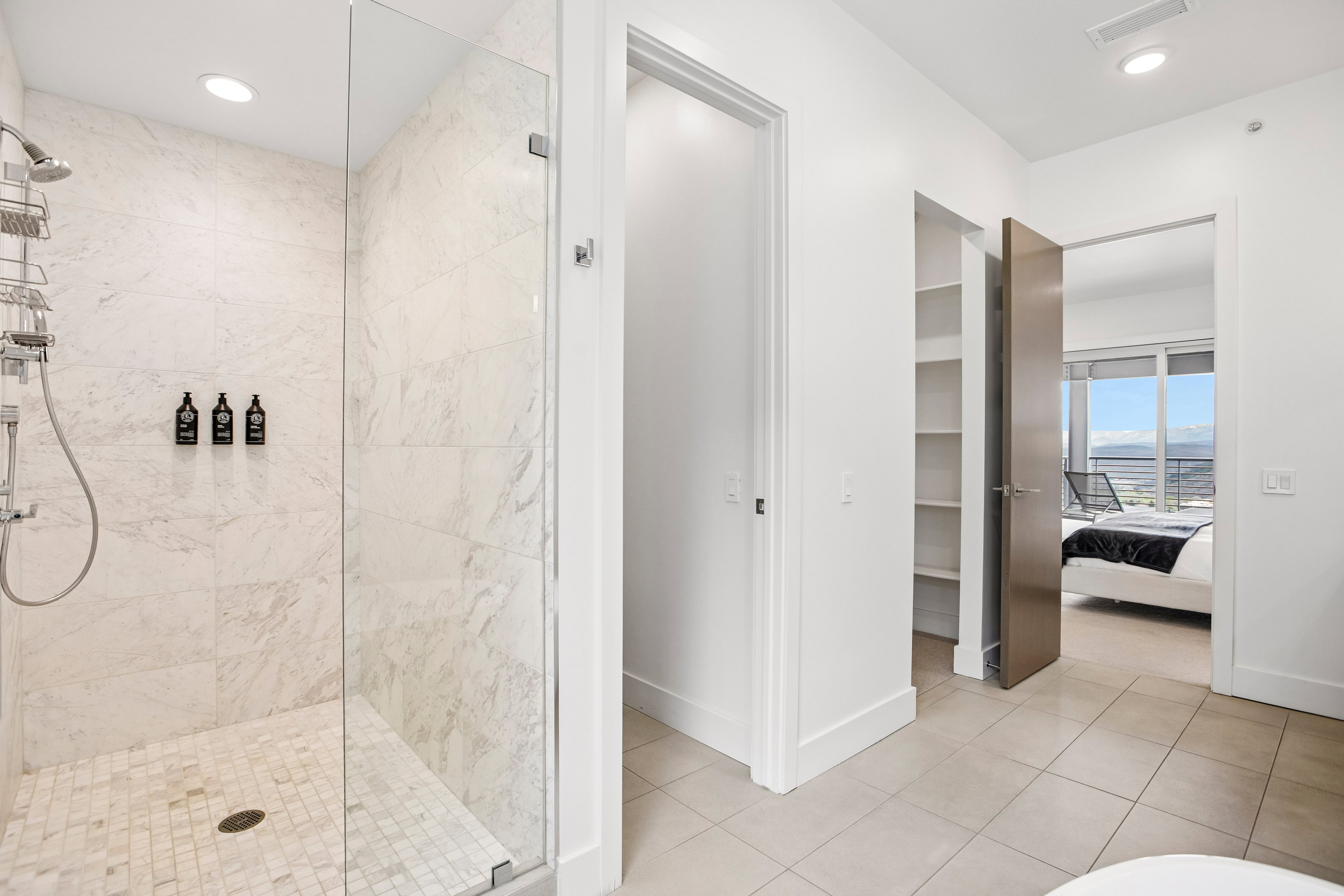 Spacious shower with large format tile walls and a mosaic tile floor, featuring a glass enclosure