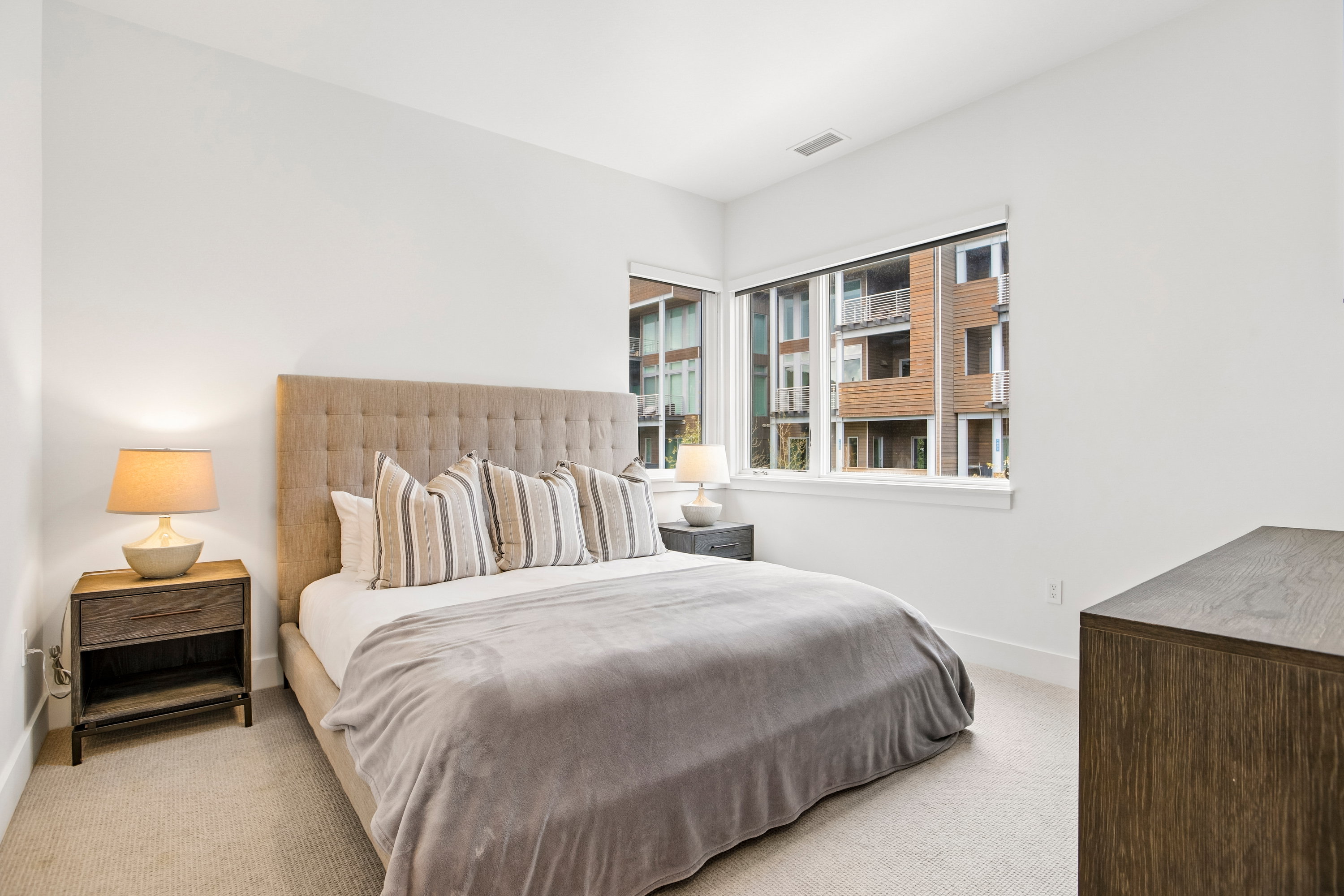 Bright room featuring large windows, plush carpeting, white walls, and a neutral color palette
