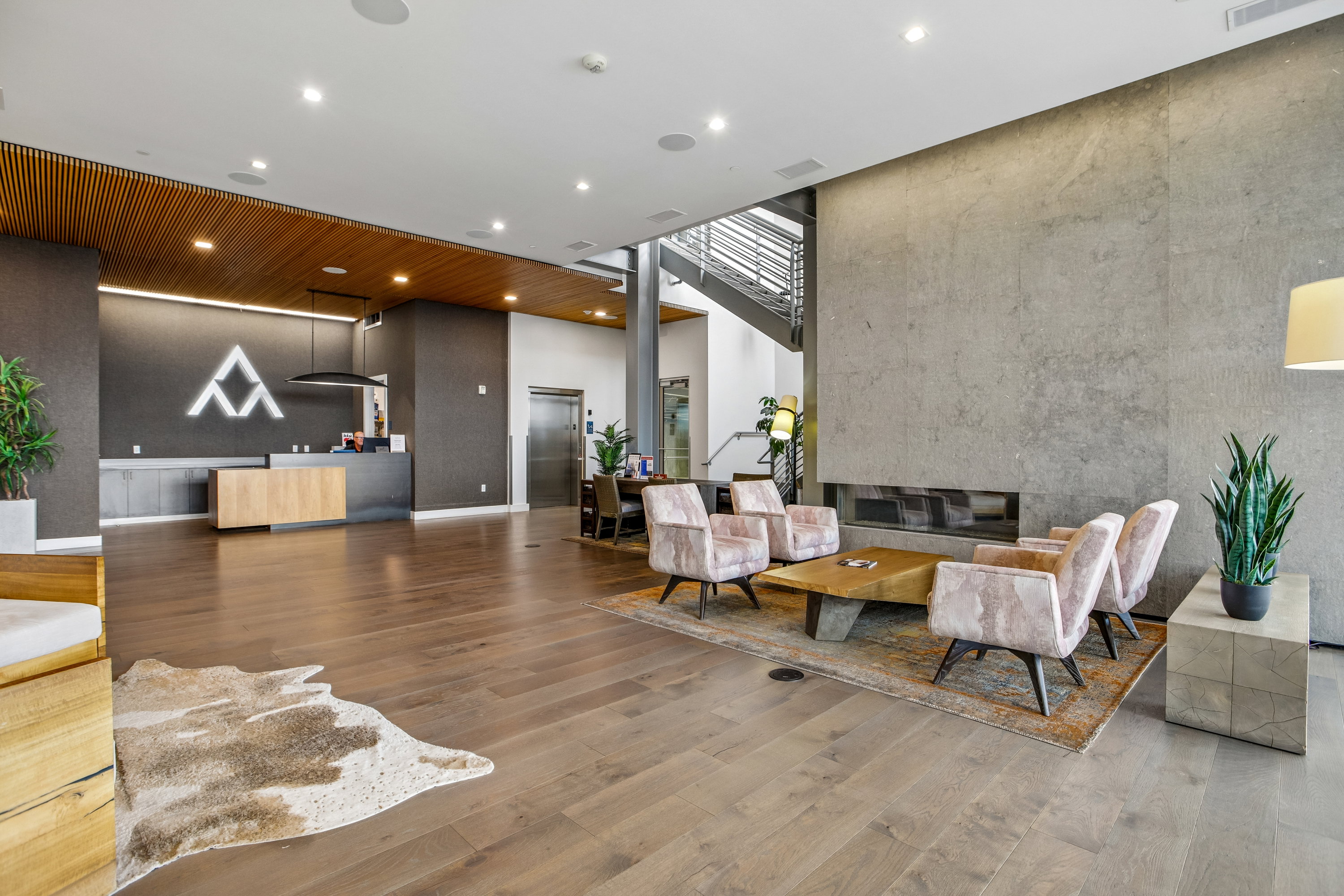 Spacious reception area featuring wood-finish flooring, a contemporary built-in fireplace, and a striking concrete accent wall