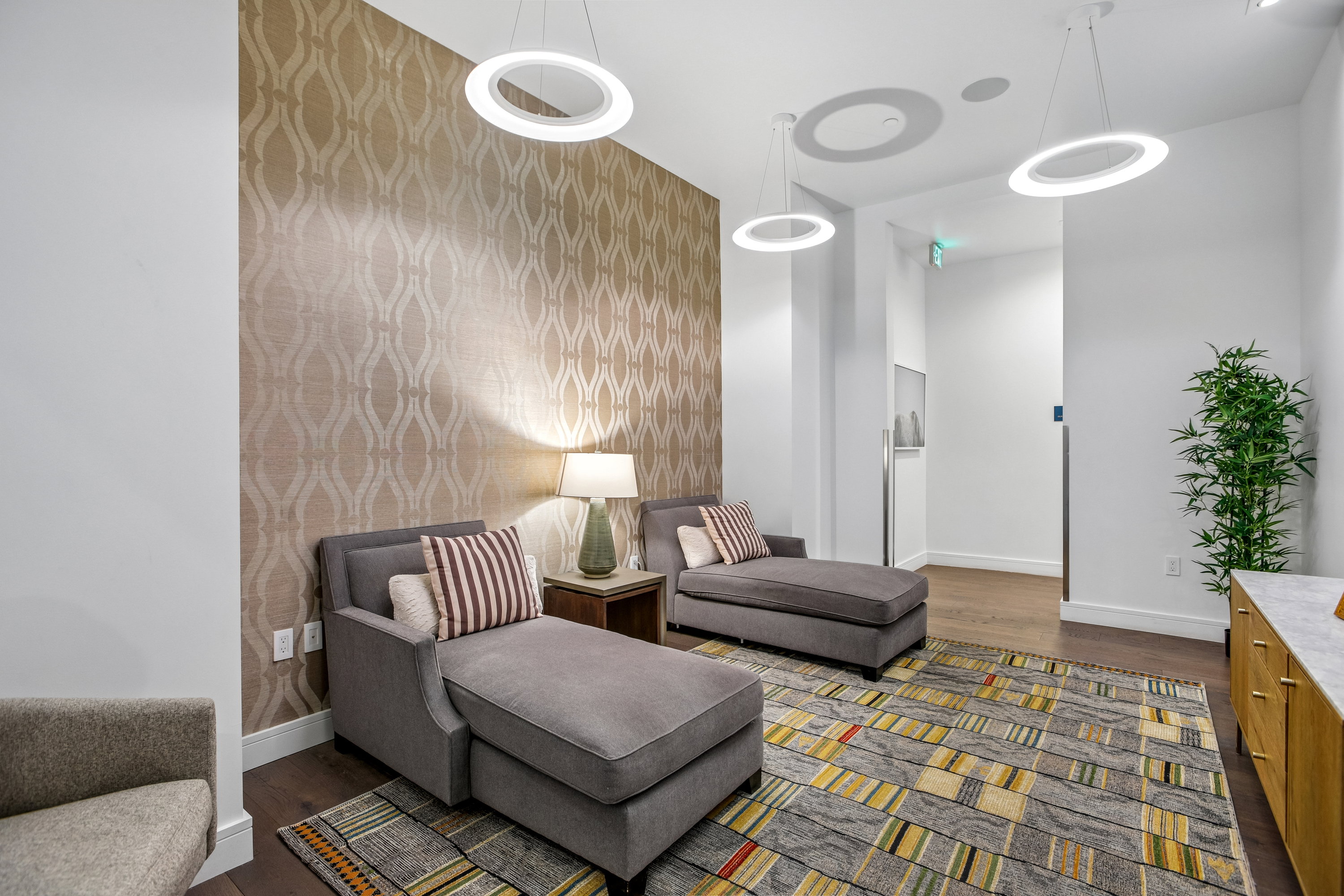 Accent wall with textured wallpaper, dark wood-finish flooring, recessed lighting, and modern ring pendant lights