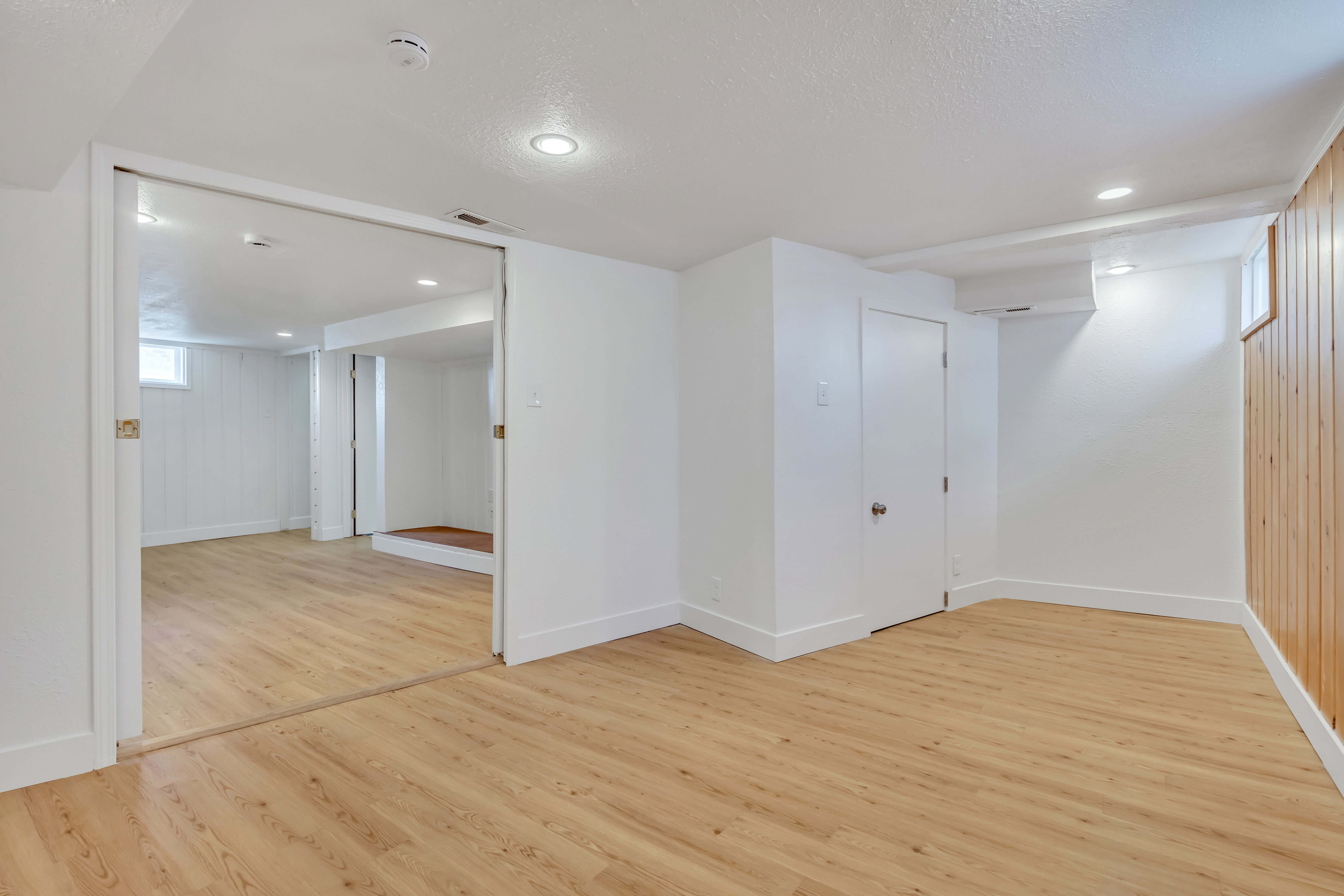 Spacious interior featuring wood-finish flooring, recessed lighting, white walls, and a wood-paneled accent wall