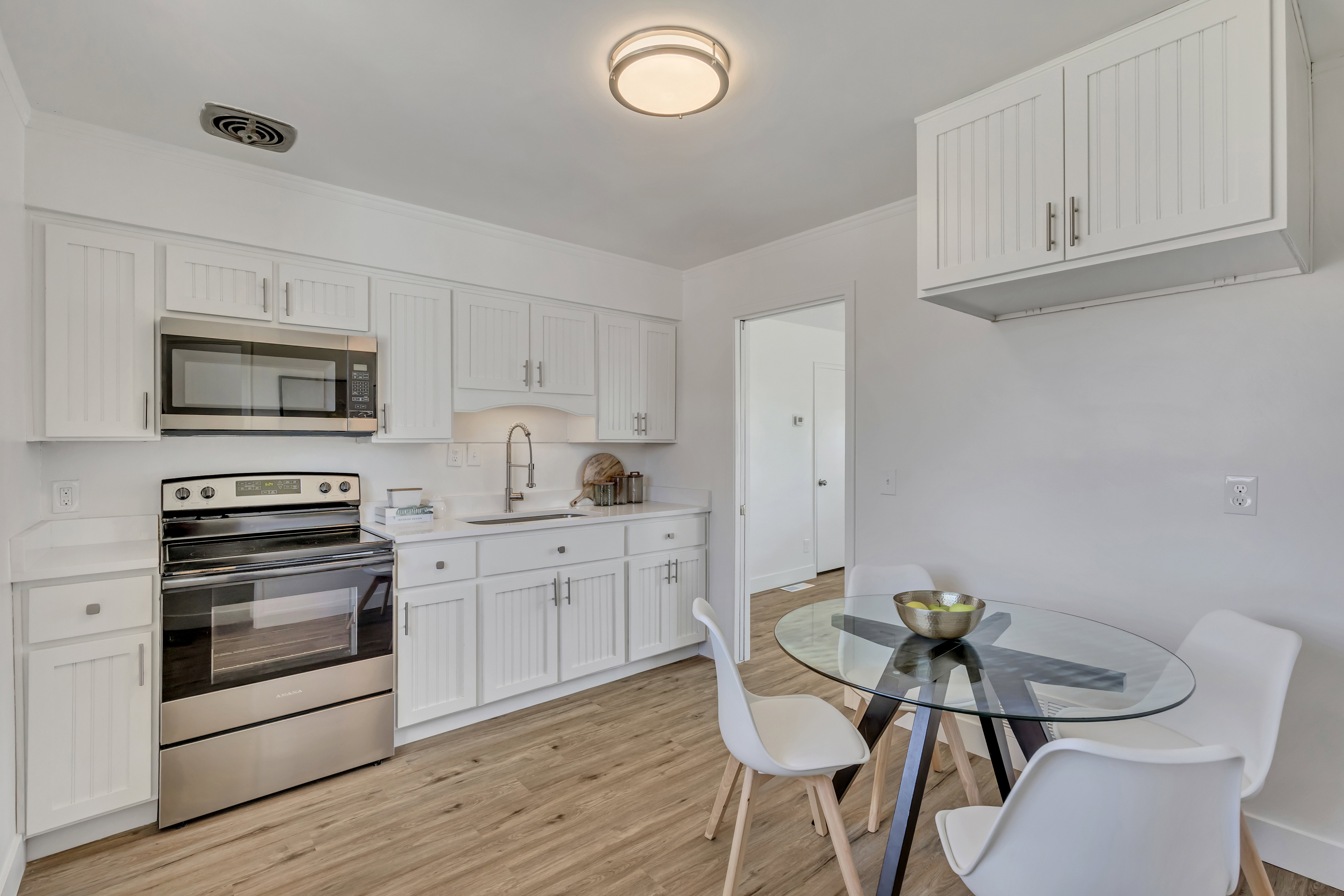 Kitchen featuring white shaker-style cabinetry, stainless steel appliances, a white tile backsplash, and light wood-finish flooring