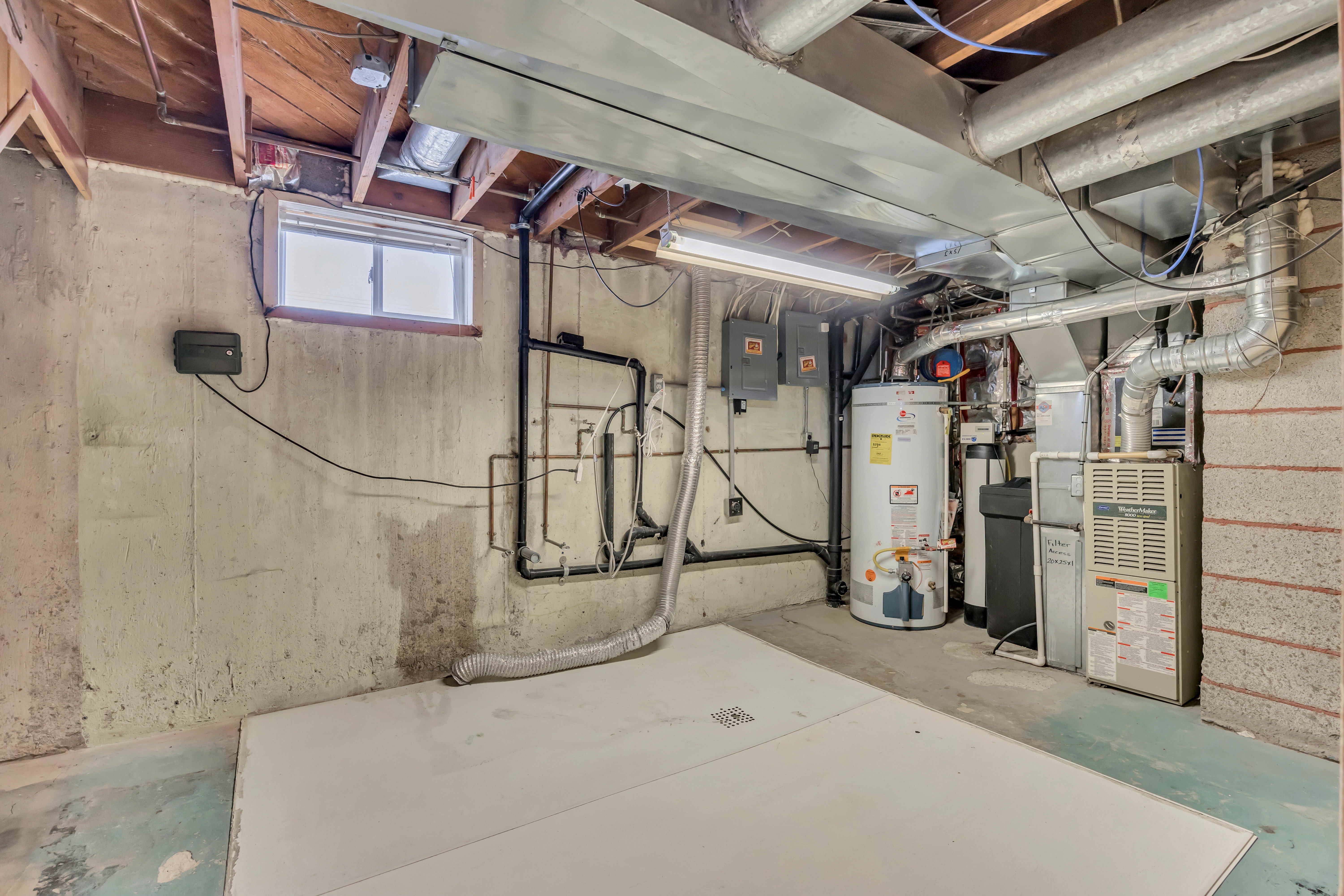 Basement utility area featuring a water heater, furnace, and exposed ductwork