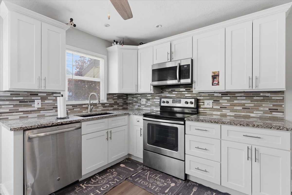 Kitchen featuring white shaker-style cabinetry, granite countertops, and a mosaic tile backsplash