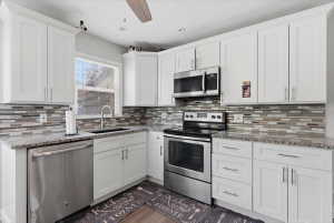 Kitchen featuring white shaker-style cabinetry, granite countertops, and a mosaic tile backsplash