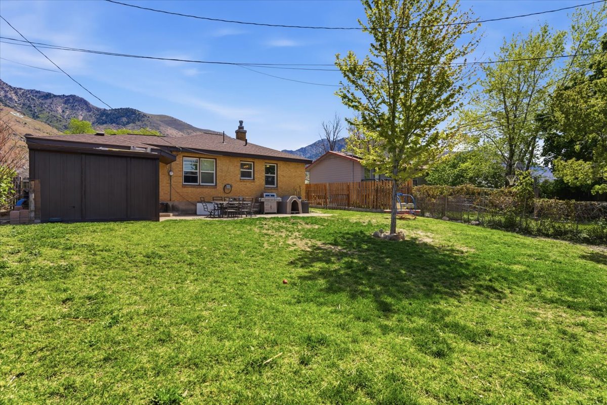 Spacious backyard featuring a sloped lawn and mature trees