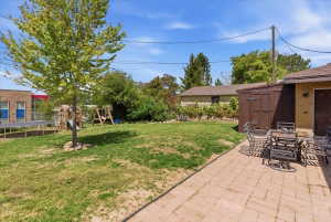 Expansive backyard featuring a paver patio, a freestanding storage shed, and mature trees