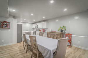 Dining area with light wood-style flooring and recessed lighting