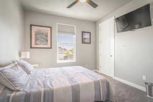 Carpeted bedroom with a ceiling fan and baseboards