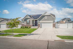 Craftsman-style home with brick siding, a gate, concrete driveway, roof mounted solar panels, and a garage