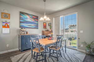 Dining area with dark wood-type flooring and hanging lights