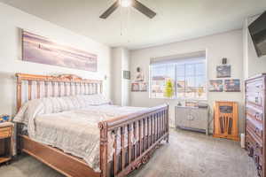 Carpeted bedroom featuring a ceiling fan and a textured ceiling
