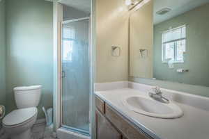 Bathroom featuring a walk-in shower with a glass enclosure, white toilet, vanity with integrated sink, and an overhead lighting fixture