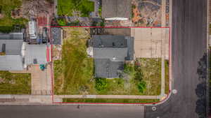 Aerial view of a residential property featuring a dark-shingle roof, concrete driveway, and a corner lot