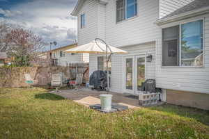 White siding exterior with a ground-level patio, double glass doors, and an exterior wall lantern