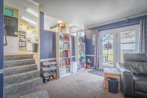 Carpeted living area featuring built-in shelving, a glass-paned double door, and direct access to a private backyard