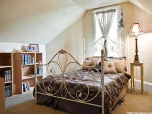 Carpeted room featuring a sloped ceiling and a window with natural light