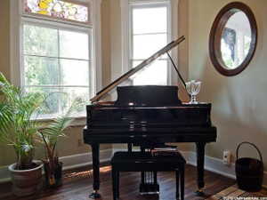 Hardwood flooring with a patterned inlay, large windows, and an ornate stained-glass transom window