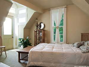 Carpeted room featuring an arched doorway with transom windows, a large double-hung window, and sloped ceilings