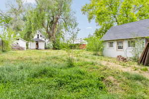 Expansive rear yard with mature perimeter trees, a wooden privacy fence, and a distant garage