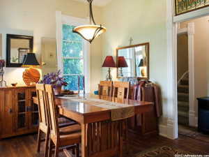 Dining area featuring wood-finish flooring, a large window, a ceiling-mounted light fixture, and an ornate stained glass transom