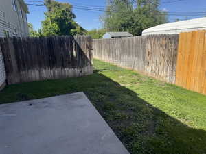Expansive outdoor space featuring a concrete patio, wood privacy fencing, and a grassy area