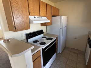 Kitchen featuring wood-finish cabinetry, a white electric range, and a white top-freezer refrigerator