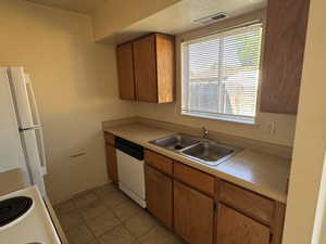 Kitchen featuring wood-finish cabinetry, a double basin stainless steel sink, and a dishwasher
