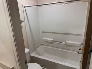 White integrated tub and shower unit featuring a built-in shelf and grab bar