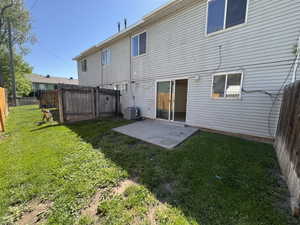 Rear exterior with light-colored siding, a concrete patio, and a sliding glass door
