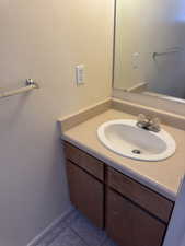 Bathroom vanity featuring a built-in sink, laminate countertop, wood-finish cabinetry, and a wall-mounted mirror